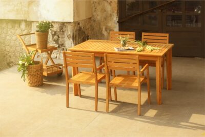 Kansas Dining Set featuring a solid teak wood dining table and chairs, placed in a rustic outdoor patio with natural fine sanded finish.